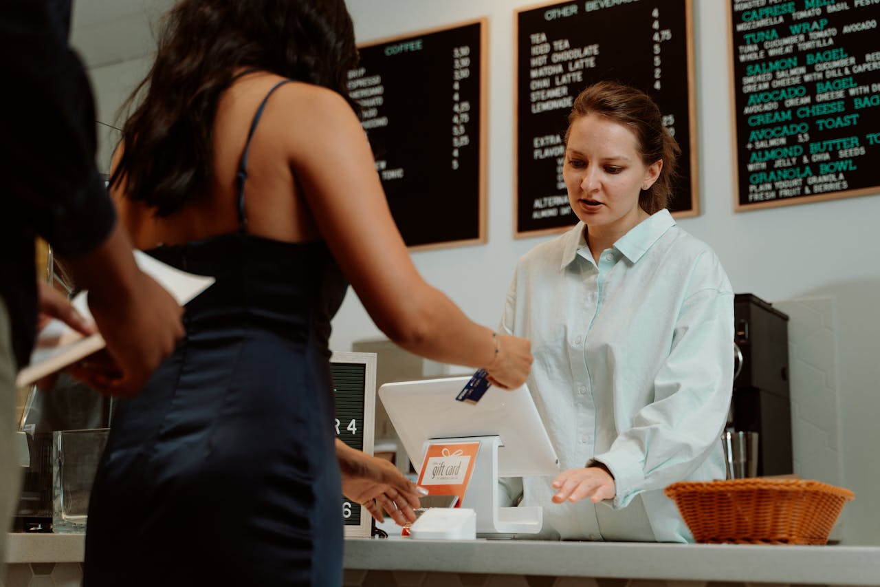 Services A customer pays with a card at a coffee shop as a barista assists.